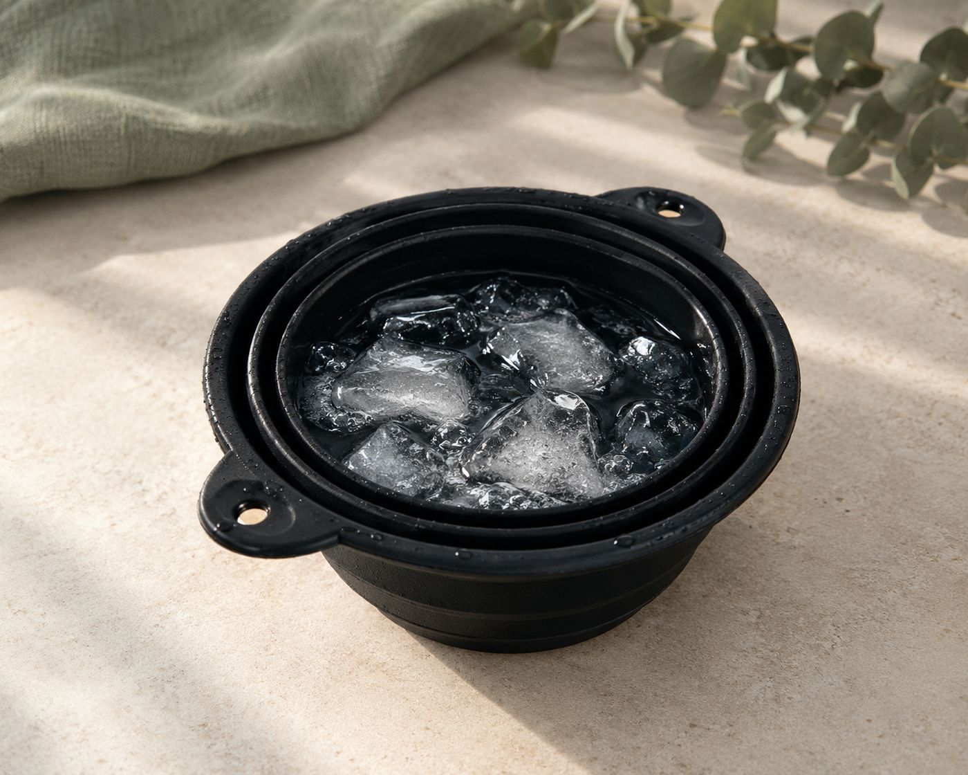 The Freeze Bowl con hielo sobre piedra clara, junto a lino salvia y eucalipto
